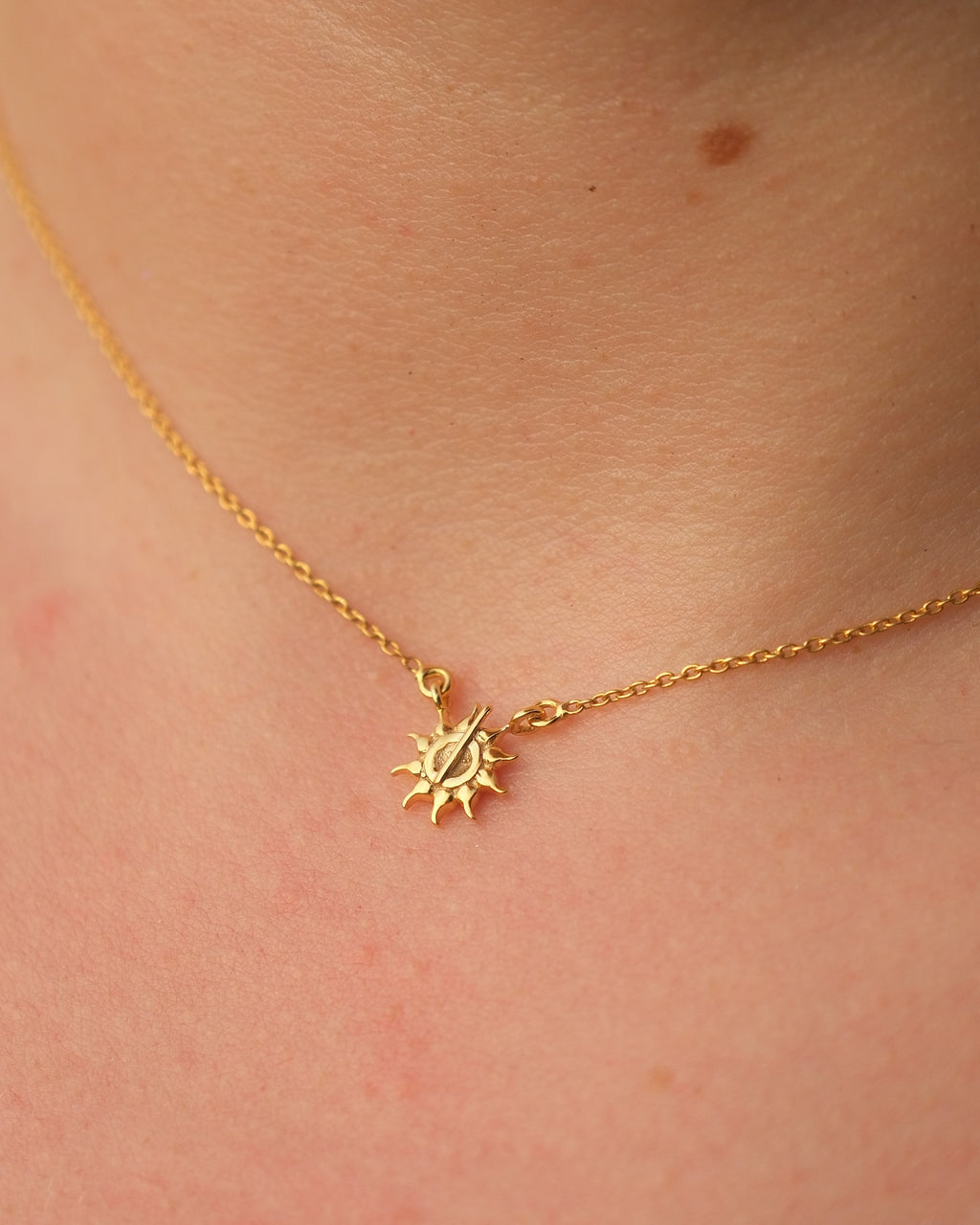 Macro shot of the sun-shaped pendant with a central line detail on 18KT gold vermeil