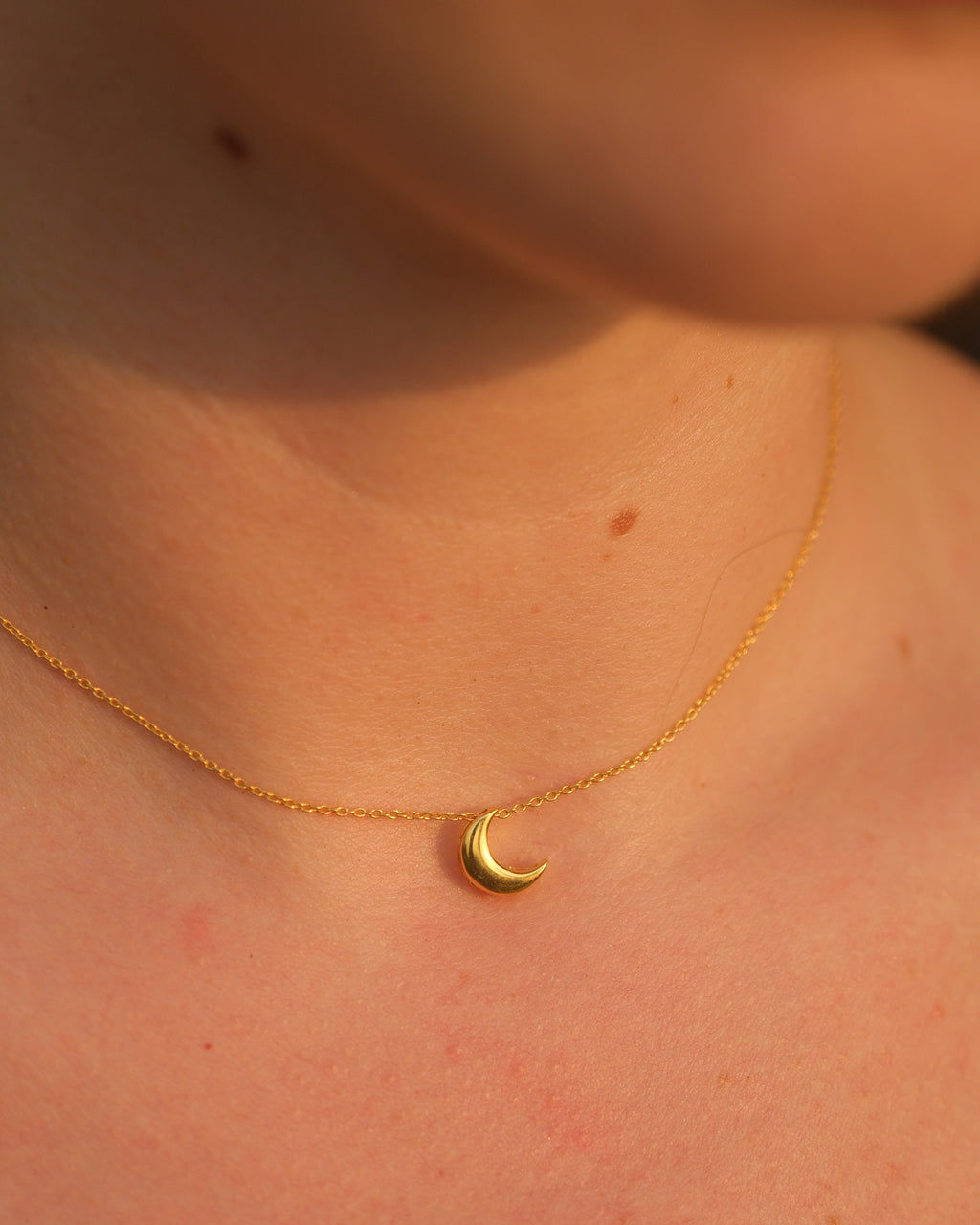 Gold necklace with a small 18KT gold vermeil crescent moon pendant on an adjustable chain