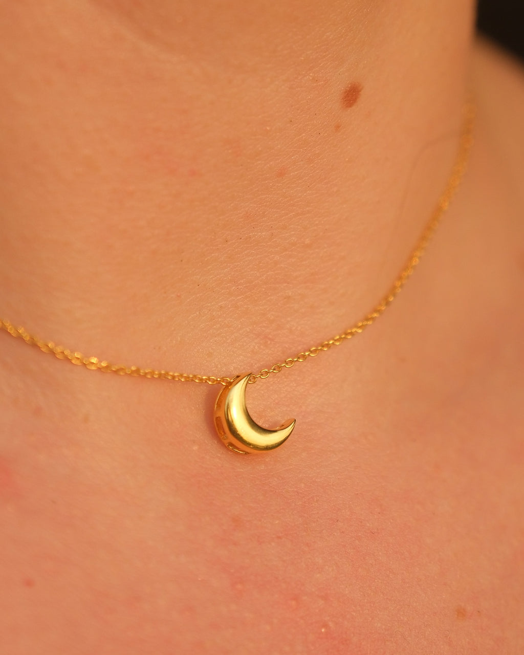 Model wearing an 18KT gold vermeil moon pendant necklace with an adjustable chain, styled elegantly