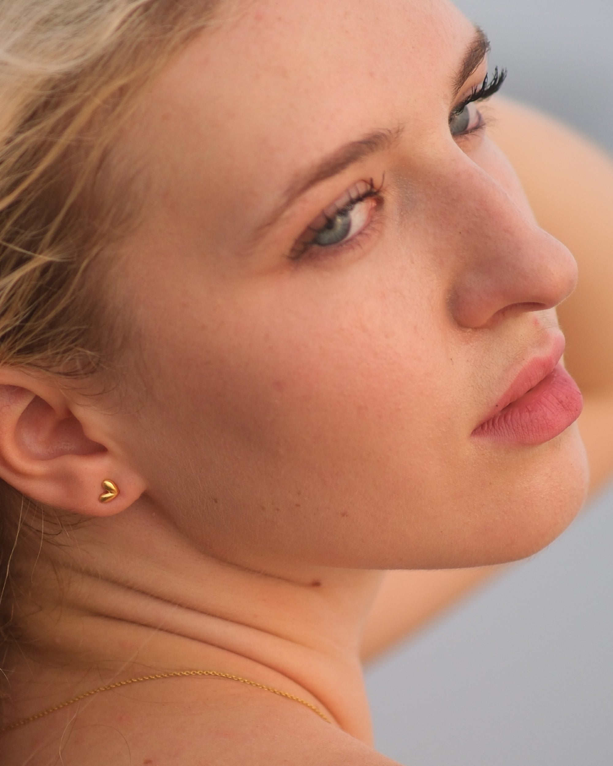 Model wearing dainty 18KT Gold Vermeil Heart Stud Earrings with raised dome design