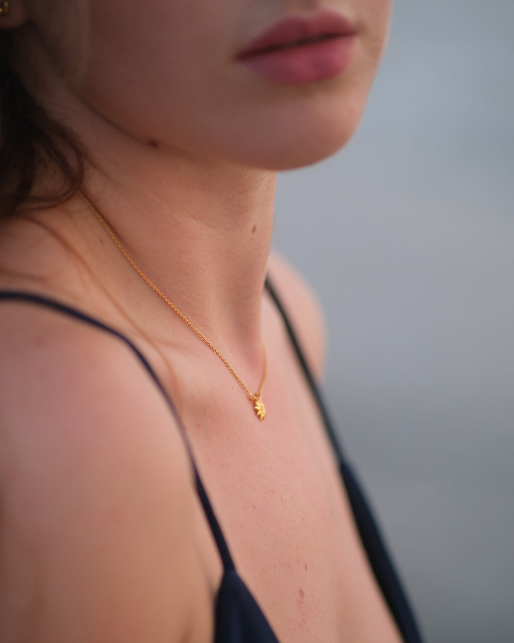 Side angle of handcrafted sun pendant necklace showcasing thickness and detail in gold vermeil