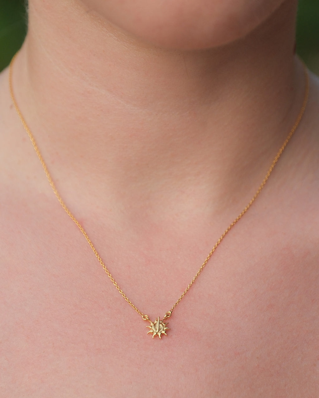 Close-up of necklace featuring sun pendant with line symbolizing light and energy, in 18KT gold vermeil finish